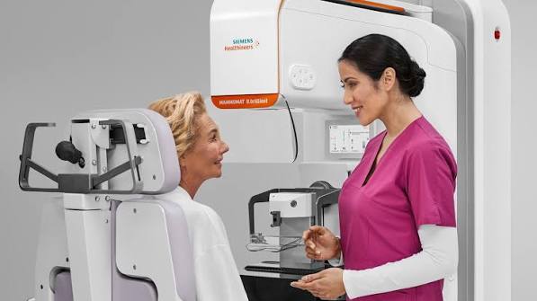 Technologist smiling with a patient beside the new Siemens mammography system