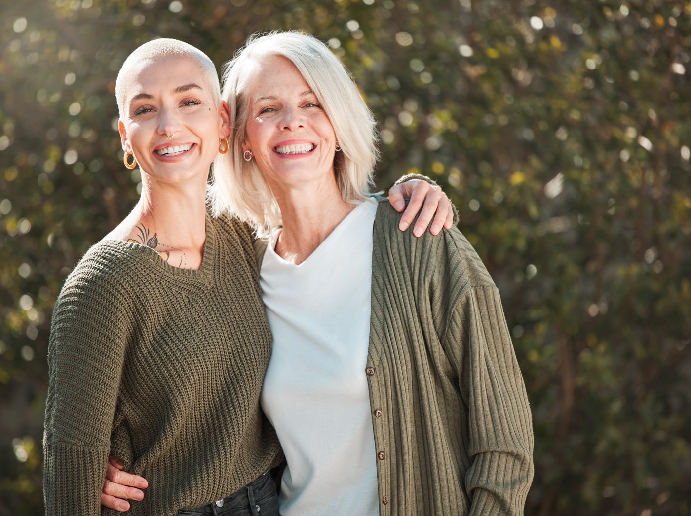 Two women smiling and embracing outdoors